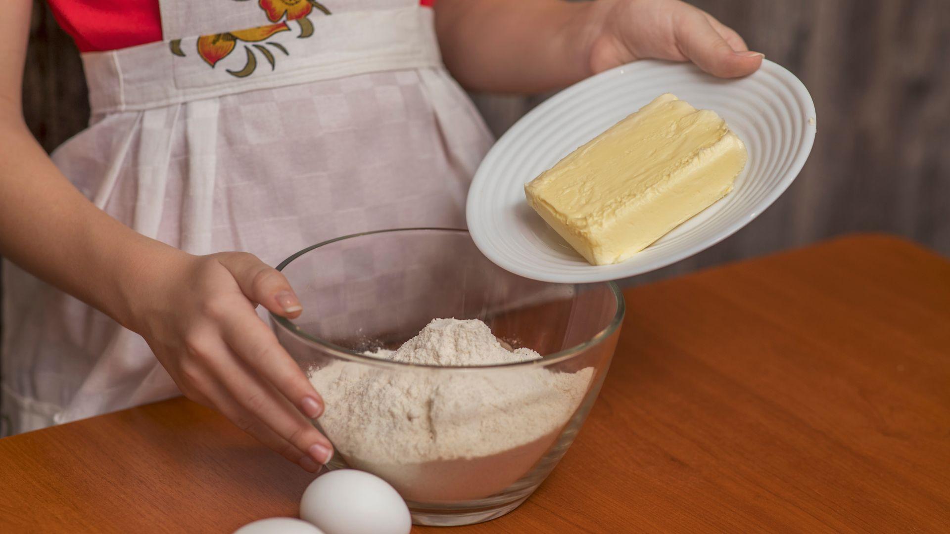 The girl adds butter to the cookie dough